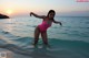 A woman in a pink bathing suit standing in the ocean.