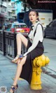 A woman sitting on top of a yellow fire hydrant.