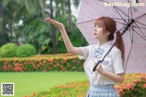 A woman in a school uniform holding an umbrella.